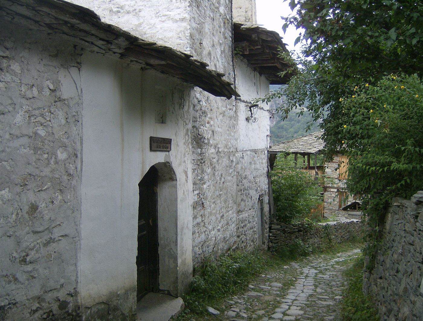 A whitewashed stone house with a slate eave on a cobbled lane in Kovachevitsa
